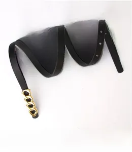 Detail of slim black leather belt featuring a chunky gold chain-link buckle for women