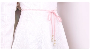 Detail of pink velvet rope waist belt with white pearls and golden pendant on lace dress