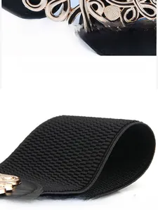 Détail de la boucle dorée gravée et de la ceinture élastique noire en grain de maïs