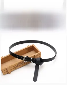 Detail of slim black PU leather belt with silver round alloy buckle and fine texture