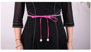 Detail of neon pink velvet waist rope with white pearls on a black dress