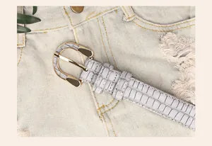 Close-up of a gray stone pattern faux leather belt with a golden horseshoe metal buckle