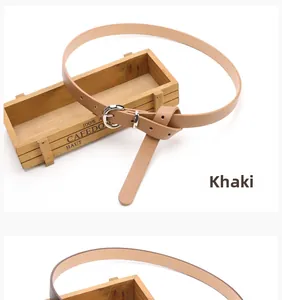 Detail view of khaki faux leather belt with silver pin buckle tied in a knot