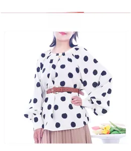 Detail of a brown leather textured belt paired with a white polka dot top and pleated skirt
