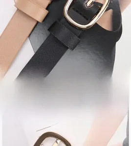 Detail of elegant black and beige leather belts with polished gold oval alloy buckles