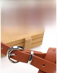 Detail shot of a brown leather belt featuring a polished silver alloy pin buckle closure