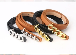 Close-up of four slim leather belts in black and brown with gold and silver link buckles