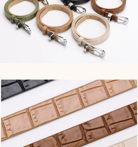 Detailed macro view of crocodile pattern faux leather belts with polished silver buckles