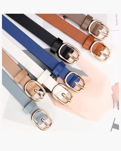 Close-up of thin faux leather belts with gold buckles in various assorted colors