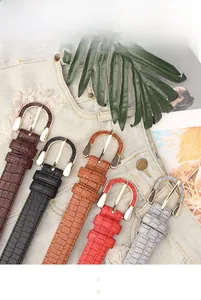 Flat lay of vintage crocodile pattern women belts with gold buckles on denim clothing
