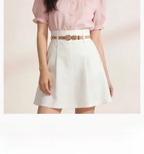 Detail of slim light brown waist belt with floral buckle on white A-line dress