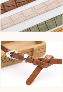 Detailed close-up of textured crocodile pattern leather belts with polished metal buckle