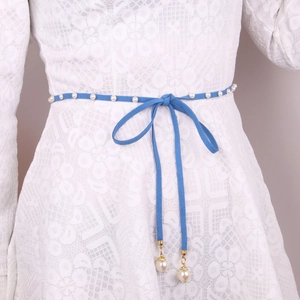 Blue velvet waist rope with faux pearls and bow tied over a white lace dress