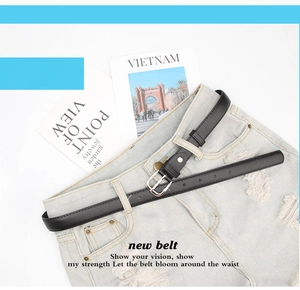 Detail of slim black belt with silver pin buckle styled on light blue distressed jeans