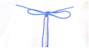 Dettaglio cintura intrecciata blu con nappe annodata a fiocco su vestito in pizzo
