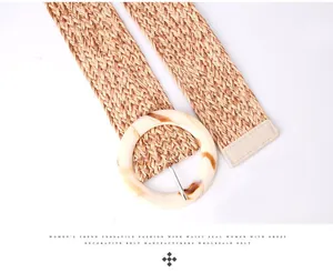 Détail d'une ceinture large en paille tressée avec une grande boucle ronde en résine marbrée