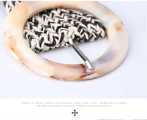 Détail d'une ceinture tressée avec une grande boucle ronde en résine au fini ambre