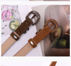 Detail of slim faux leather belts with horseshoe buckles in coffee and brown tones