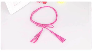 Vista dettagliata della cintura intrecciata rosso rosa con accenti di frange a nappa