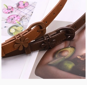 Close-up of slim brown and tan floral waist belts with matte buckles on colorful magazine