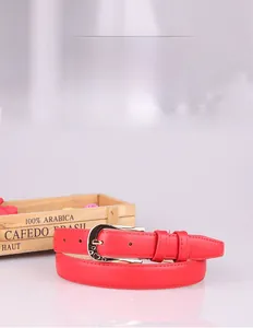 Detail of red thin leather belt with gold hollow heart buckle and metal pin buckle