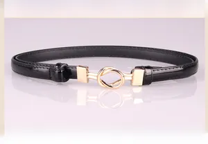 Detail of slim black waist belt featuring a gold-tone knot buckle with mirror reflection