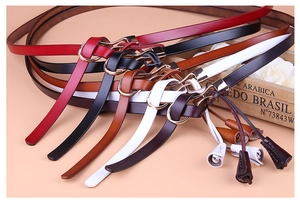 Détail de ceintures fines pour femmes en cuir coloré avec boucles dorées et pompons décoratifs
