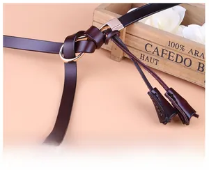 Détail d'une ceinture en cuir marron foncé avec boucle ronde dorée et design noué