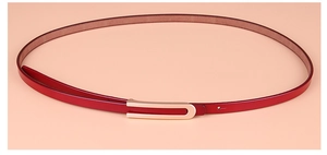 Détail d'une ceinture fine en cuir rouge foncé pour femme avec une boucle dorée en forme de U