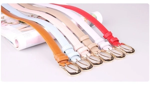 Detail of colorful PU leather belts for women with polished gold metal buckles on a magazine