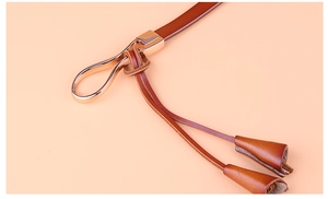 Détail d'une ceinture en cuir marron avec boucle en métal doré et surpiqûres