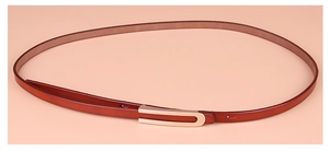 Détail d'une fine ceinture en cuir marron-rouge avec une boucle dorée en forme de U