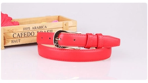 Detail of red faux leather belt featuring a gold D-ring buckle with heart shaped cutout