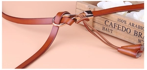 Détail d'une ceinture fine en cuir marron avec boucle dorée et décoration de gland