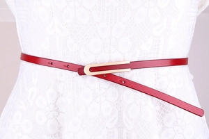 Détail de la fine ceinture en cuir rouge avec boucle dorée sur robe en dentelle