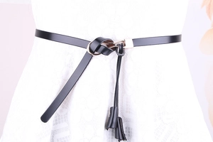 Détail de la fine ceinture en cuir verni noir avec boucle dorée sur robe en dentelle