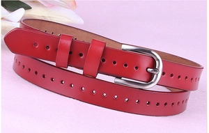 Dettaglio cintura in pelle rossa con fibbia a ferro di cavallo argento e fori decorativi