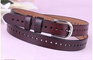 Dettaglio della cintura in pelle bordeaux con fibbia a D argento e design traforato