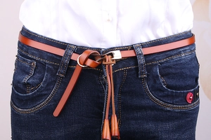Gros plan d'une ceinture en cuir marron avec boucle en métal sur un jean bleu
