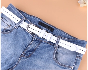 Cintura classica in pelle bianca con fibbia in metallo argentato su jeans denim blu