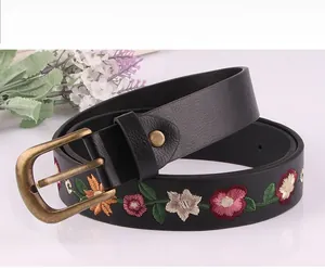 Detailed close-up of vintage flower embroidery on a black leather belt with metal buckle