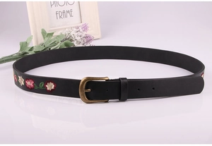Detailed macro shot of vintage floral embroidery on black leather belt with bronze buckle