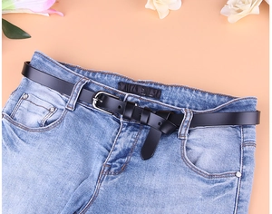 Detail eines schmalen schwarzen Ledergürtels mit silberner Nadelschnalle auf hellblauer Jeans