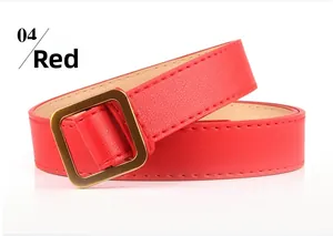 Détail d'une ceinture rouge en cuir texturé avec une boucle carrée en métal doré sur blanc