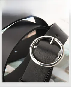 Detail view of black faux leather belt with a round silver alloy buckle and lychee texture