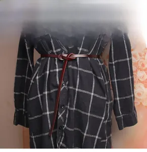 Detail of dark brown leather slim belt styled in a knot over a plaid dress