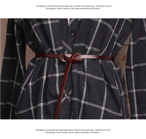 Detail of red-brown leather slim belt tied on a black and white checkered shirt
