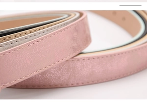 Detailed macro shot of pink faux leather belt texture with metallic finish and fine stitching