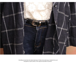 Detail of thin black leather belt with gold buckle styled with blue jeans and lace top