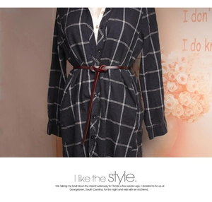 Detail of burgundy slim leather belt tied around a dark plaid dress for waist styling